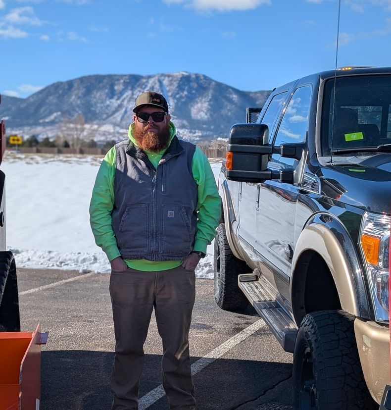Al Mason standing between his loader and plow truck