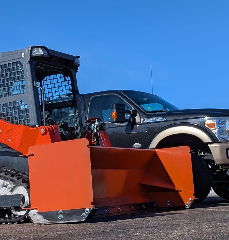 Kubota loader with snow pusher in front of a pickup