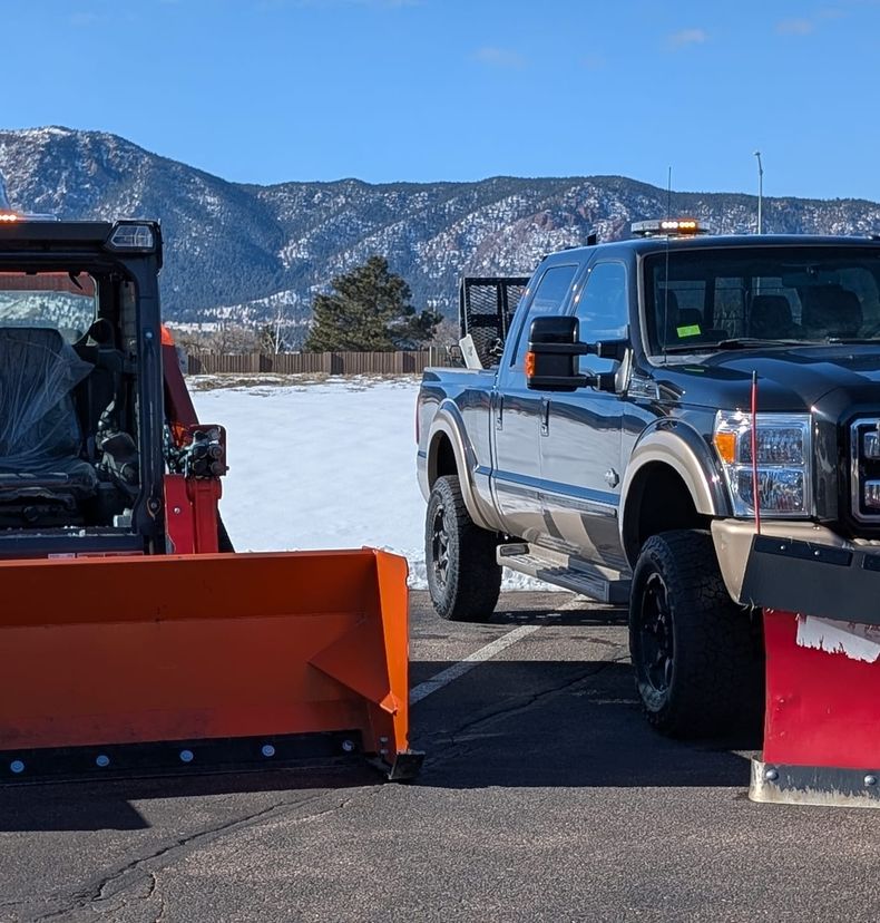 Loader and plow truck staged in a parking lot