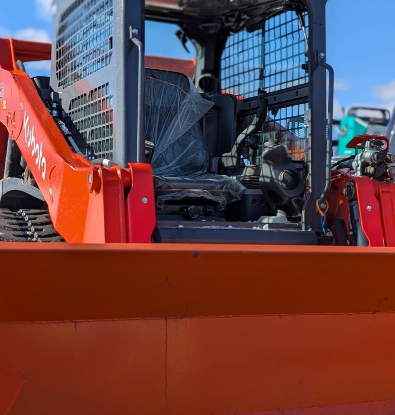 Kubota track loader with an orange snow pusher