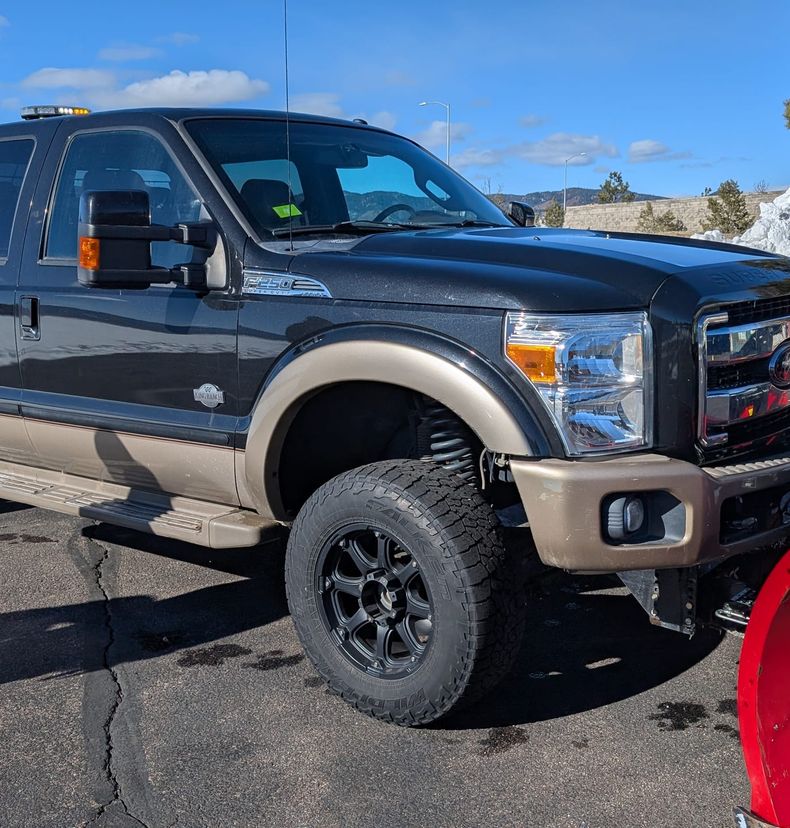 Black and tan Ford plow truck in a cleared lot